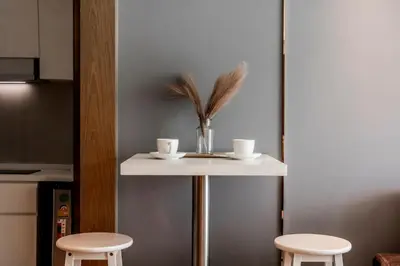 a small white table with two cups and two stools at La Vita Phuket by Beringela in Rawai Beach