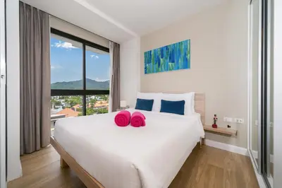 a bedroom with a large bed with two pink slippers on it at Diamond Bangtao Beach 1 bedroom in Bang Tao Beach