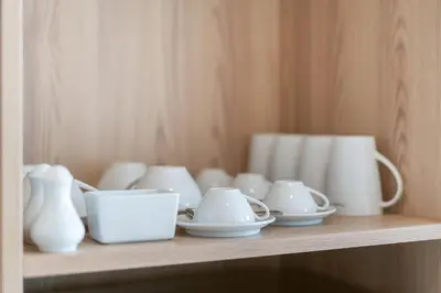 a shelf with white vases and cups on it at Diamond Bangtao Beach 1 bedroom in Bang Tao Beach