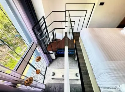 a room with a staircase and a bed and a window at Utopia Naiharn Loft Condo in Rawai Beach