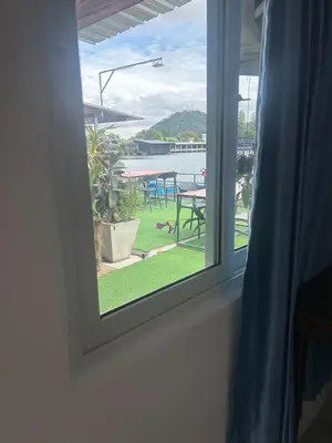 a window with a view of a patio with a table at Riverside Hostel Phuket in Phuket Town