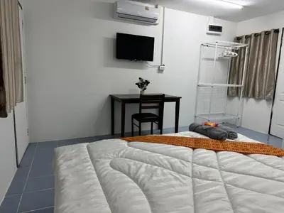 a bedroom with a large bed and a table at Riverside Hostel Phuket in Phuket Town