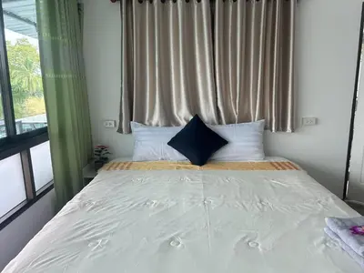 a bed with white sheets and pillows in a bedroom at Riverside Hostel Phuket in Phuket Town