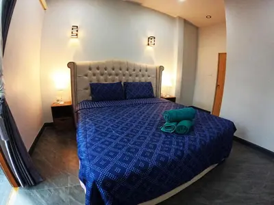 a bed with a blue comforter and a green pillow on it at Krabi Top Sea Hill Villa in Klong Muang Beach