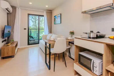 a kitchen and a living room with a table and a counter at Space 404 - 1BDR with Coworking, Pool & Gym Access in Bang Tao Beach