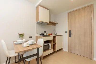 a kitchen and dining room with a table and a microwave at Space 404 - 1BDR with Coworking, Pool & Gym Access in Bang Tao Beach