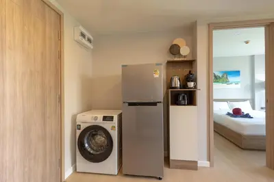 a kitchen with a washing machine and a bed at Space 404 - 1BDR with Coworking, Pool & Gym Access in Bang Tao Beach