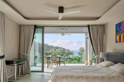 a bedroom with a bed and a balcony with a view at Spectacular two bed penthouse amazing sea views in Patong Beach