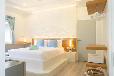 a bedroom with a white bed with blue pillows at Stylish Studio with Pool - 8' walk to Rawai Beach - 