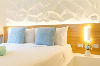 a bedroom with a bed with blue and white pillows at Stylish Studio with Pool - 8' walk to Rawai Beach - 