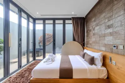 a bedroom with a bed and large glass windows at V253 Brand New 2BR with Pool and Full Kitchen in Thalang