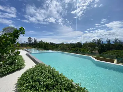 a large swimming pool with blue water and trees at 2bdr New Apartment in Laguna near Bangtao Beach LBS-4203 in Bang Tao Beach