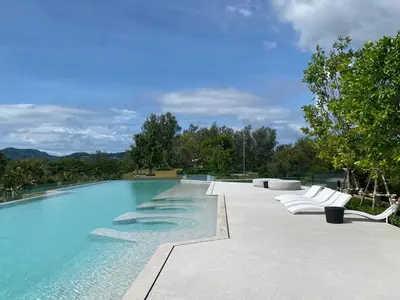 a swimming pool with white lounge chairs and trees at 2bdr New Apartment in Laguna near Bangtao Beach LBS-4203 in Bang Tao Beach