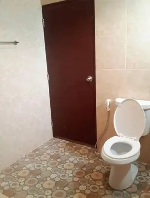 a bathroom with a toilet and a brown door at Pluemjai mansion in Kathu