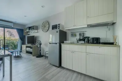 a kitchen with white cabinets and a refrigerator and a table at Cozy apartment by the sea F410 in Nai Yang Beach