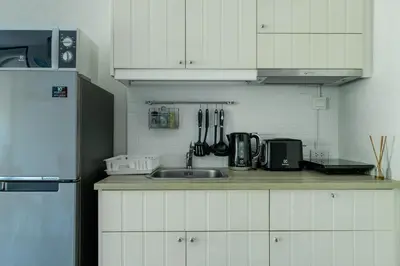 a kitchen with white cabinets and a sink and a refrigerator at Cozy apartment by the sea F410 in Nai Yang Beach