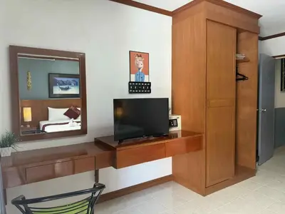a room with a television on a desk with a mirror at Flowernight Guesthouse in Kata Beach