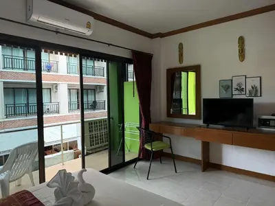 a bedroom with a bed and a television and a balcony at Flowernight Guesthouse in Kata Beach
