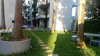 a grassy area with palm trees in front of a building at palmyrah apartment 300 meters from surin beach in Ban Nong Chaeng