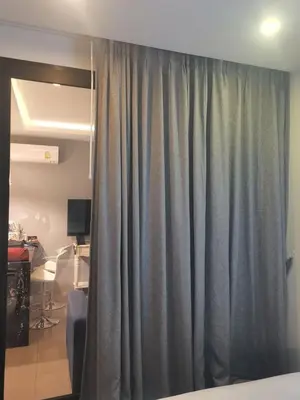 a gray curtain in a room with a desk at palmyrah apartment 300 meters from surin beach in Ban Nong Chaeng