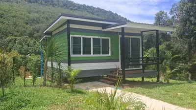 a green tiny house with a hill in the background at Greenview Room and Restaurant