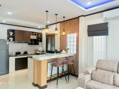 a kitchen with a bar with stools and a couch at PS House Bangtao in Bang Tao Beach