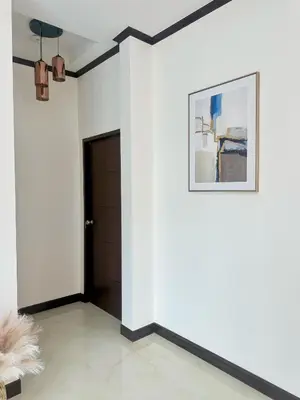 a room with a white wall with a picture and a door at PS House Bangtao in Bang Tao Beach