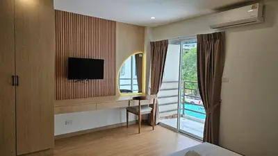 a hotel room with a desk with a television and a window at CK House in Patong Beach