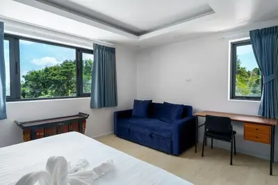 a bedroom with a bed and a blue couch and a desk at Tilawan Villa by G Estate Phuket in Ban Klang