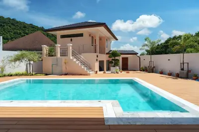 a villa with a swimming pool in front of a house at Tilawan Villa by G Estate Phuket in Ban Klang