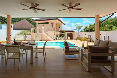 a living room with a table and chairs and a pool at Tilawan Villa by G Estate Phuket in Ban Klang
