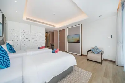 a bedroom with a large white bed and a chair at Luxury 2BR Suite Lakeside Angsana Laguna in Phuket Town