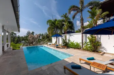a pool with chairs and umbrellas next to a house at 50% Off Baan Angelo 3 Bed Pool Villa Kata Hill in Kata Beach