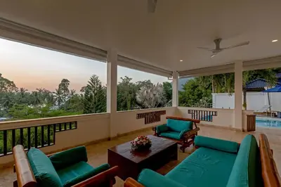 a large living room with green furniture and large windows at 50% Off Baan Angelo 3 Bed Pool Villa Kata Hill in Kata Beach