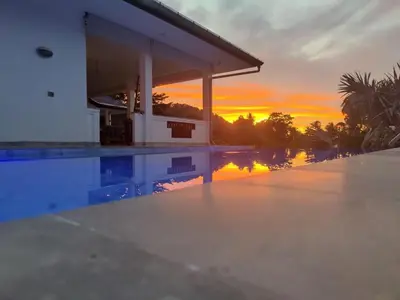 a sunset over a swimming pool at a house at 50% Off Baan Angelo 3 Bed Pool Villa Kata Hill in Kata Beach