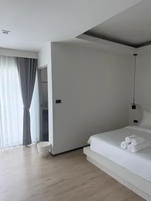 a white bedroom with a bed and a large window at Jellyfish Residence Patong in Patong Beach