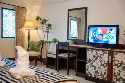 a living room with a tv and a desk with a television at Nyonya Maison Boutique Hotel Phuket Old Town in Phuket Town