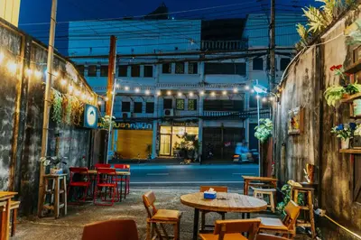 a patio with tables and chairs at night at Nyonya Maison Boutique Hotel Phuket Old Town in Phuket Town