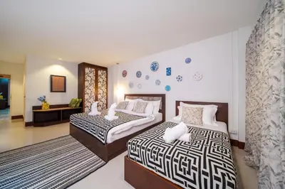 a bedroom with two beds and a living room at Nyonya Maison Boutique Hotel Phuket Old Town in Phuket Town