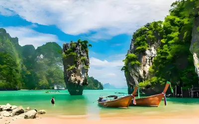 two boats on a beach with cliffs in the water at XX GO INN Patong Beach Phuket - โกอินน์ ป่าตอง in Patong Beach