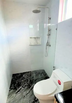 a bathroom with a white toilet and a shower at Chalong pool villa in Ban Na Bon
