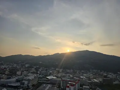 a city with the sun setting on a mountain at PATONG TOWER Luxury Large Apartments in Patong Beach