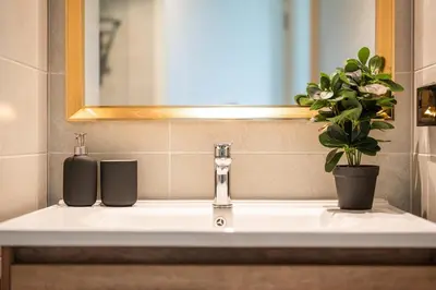a bathroom sink with a plant and a mirror at Modern 1BR Condo w Balcony Near Central Phuket in Ban Na Khua