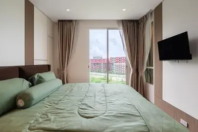 a bedroom with a large bed with a large window at Modern 1BR Condo w Balcony Near Central Phuket in Ban Na Khua