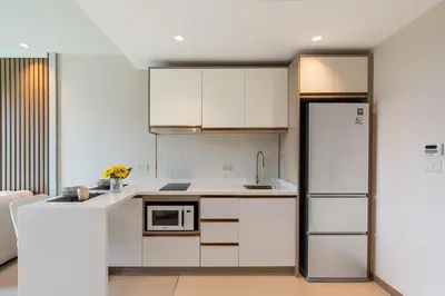 a kitchen with white cabinets and a refrigerator at Modern 1BR Condo w Balcony Near Central Phuket in Ban Na Khua