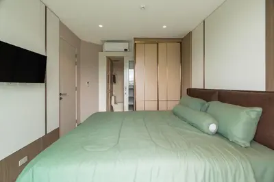a bedroom with a large bed with green pillows at Modern 1BR Condo w Balcony Near Central Phuket in Ban Na Khua