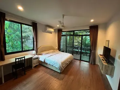a bedroom with a bed and a desk and windows at Rawai Beach Villa in Nai Harn Beach