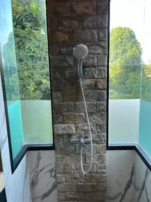 a shower in a room with a brick wall at Rawai Beach Villa in Nai Harn Beach