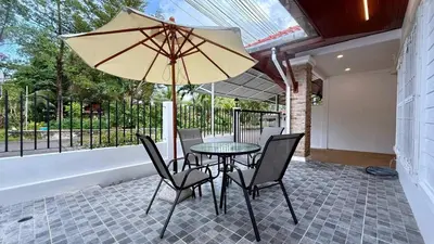 a table with chairs and an umbrella on a patio at Secret Valley near Phuket Town in Kathu