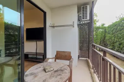 a room with a table and a balcony with a television at C239 Best Spot Beachfront 1BR Near Top Beaches in Rawai Beach